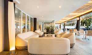 En avkopplingsområde med vita soffor och bord, omgiven av glasväggar och moderna möbler. (AI-genererad text)