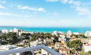 Utsikt över en kuststad med byggnader, träd och hav i bakgrunden. (AI-genererad text)