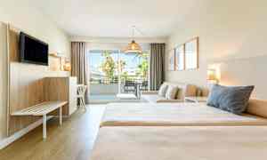 Ett hotellrum med två sängar, en sittgrupp och balkong med utsikt. (AI-genererad text)