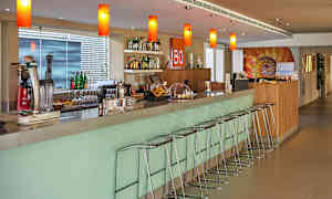 En modern bardisk med barstolar samt flaskor och glas på hyllor och bänkar. (AI-genererad text)