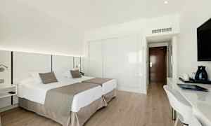 Ett hotellrum med två enkelsängar, skrivbord och TV. (AI-genererad text)