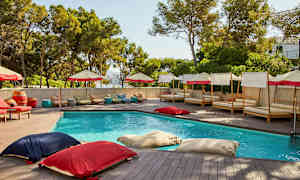 En utomhuspool omgiven av solsängar och parasoller. (AI-genererad text)