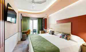 Ett modernt hotellrum med två sängar, grön inredning och en balkong med utsikt. (AI-genererad text)