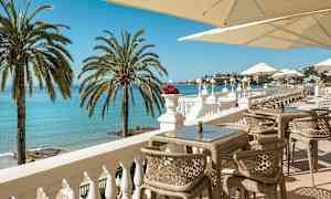 En terrass med utsikt över havet, solstolar och parasoll. (AI-genererad text)