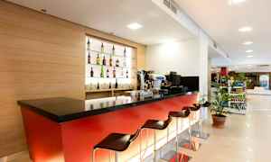 En modern hotellbar med röda paneler, svart bänkskiva och flera barstolar. (AI-genererad text)