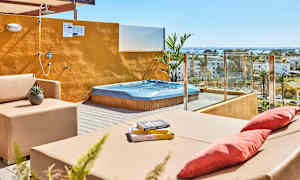 Terrass med bubbelpool, sittmöbler och öppen dusch med utsikt över omgivningen. (AI-genererad text)