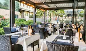 Utomhusrestaurang med dukade bord och dekorerade stolar. (AI-genererad text)