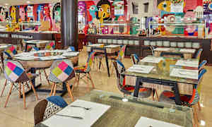 Inredning av en restaurang med färgglada stolar och dekorerade väggar. (AI-genererad text)