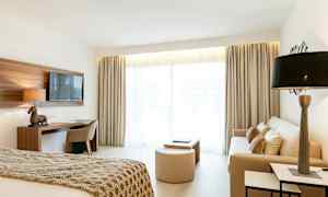 Bild av ett ljust hotellrum med bädd, soffa och skrivbord. (AI-genererad text)