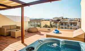 Terrass med bubbelpool, soffa och utsikt över omgivande byggnader. (AI-genererad text)