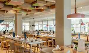 Restaurang med ljusa möbler och dekorerat tak. (AI-genererad text)