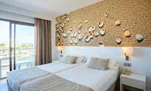 Hotellrum med två enkelsängar, dekorativ tavla med snäckor och balkong med utsikt. (AI-genererad text)