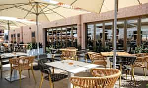 Uteservering med bord, stolar och parasoller. (AI-genererad text)