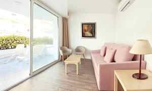 Soffa med rosa klädsel, vardagsrumsbord, två stolar och fönster med utsikt mot terrassen. (AI-genererad text)