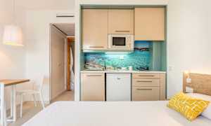 Ett enkelt hotellrum med ett litet kök och en säng. (AI-genererad text)