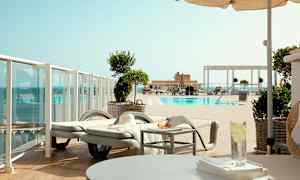 Utsikt över en pool med solstolar och parasoller. (AI-genererad text)