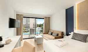 Ett hotellrum med en dubbelsäng, soffa, och balkong som vetter mot en pool. (AI-genererad text)