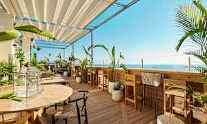 En terrass med trädgårdsmöbler och växter med utsikt över havet. (AI-genererad text)