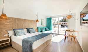 Hotellrum med en dubbelsäng, en soffa med kuddar, en liten matplats och en balkong. (AI-genererad text)