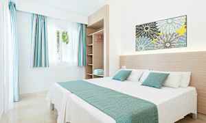 Ett ljust och modernt hotellrum med en dubbelsäng och öppna hyllor. (AI-genererad text)