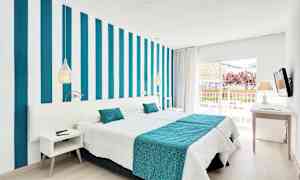 Ett modernt hotellrum med randig vägg, vita och turkosa sängkläder samt en balkong med utsikt. (AI-genererad text)