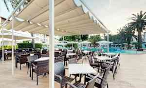 En uteservering med bord och stolar under en pergola nära en pool. (AI-genererad text)