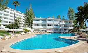 En utomhuspool med solstolar och parasoller framför en vit byggnad, omgiven av träd. (AI-genererad text)