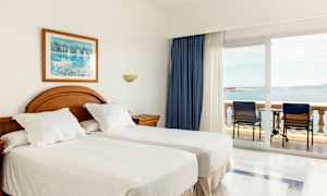 Hotellrum med två enkelsängar och balkong med havsutsikt. (AI-genererad text)