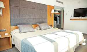 Bild som visar ett modernt hotellrum med en dubbelsäng, en garderob och en väggmonterad TV. (AI-genererad text)