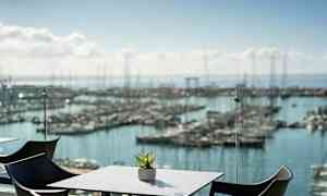 En utsikt över en småbåtshamn med bord och stolar i förgrunden. (AI-genererad text)