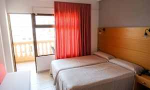 Hotellrum med två enkelsängar, röd gardin och balkong. (AI-genererad text)