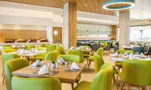 Interiör av en restaurang med gröna stolar och dukade bord. (AI-genererad text)