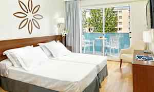 Bild av ett ljust hotellrum med två enkelsängar, en dekorativ väggprydnad, en balkong med utemöbler samt ljusa gardiner. (AI-genererad text)