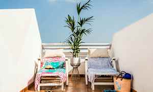 Två solstolar med handdukar och kuddar står på en terrass med en blomkruka mellan sig. (AI-genererad text)