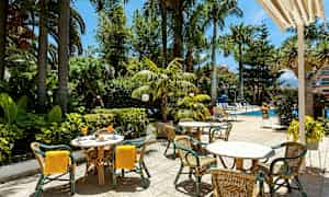 Utomhusservering med bord och stolar nära en pool och lummig vegetation. (AI-genererad text)