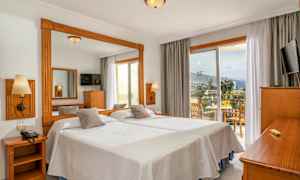 Hotellrum med två enkelsängar, en spegel, en TV och en balkong med sittplats samt utsikt. (AI-genererad text)