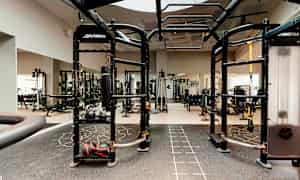 Ett gym med olika träningsredskap som kettlebells, boxsäck och styrketräningsmaskiner. (AI-genererad text)