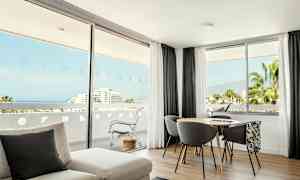 Ett ljust rum med stora fönster som visar utsikt mot havet och grönska. (AI-genererad text)