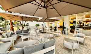 Uteservering med soffor och bord under parasoller. (AI-genererad text)