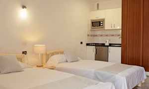 Två enkelsängar i ett rum med köksdel. (AI-genererad text)