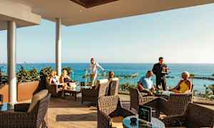 Personer som sitter på en terrass med havsutsikt. (AI-genererad text)