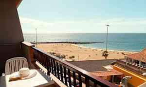 En balkong med utsikt över en sandstrand och havet. (AI-genererad text)