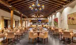 En restaurang med ett högt träbjälktak, många bord och stolar. Väggarna är dekorerade med konstverk. (AI-genererad text)