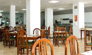 Ett kafé eller restaurang med trästolar och bord samt vita pelare i ett stort öppet utrymme. (AI-genererad text)