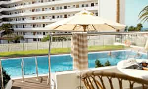 Bild med en pool, parasoll och balkong med utsikt över ett bostadsområde. (AI-genererad text)