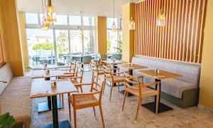 Ett modernt café med bord och stolar samt ljusa färger. (AI-genererad text)