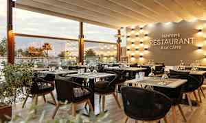 Solbelyst restaurangmiljö med elegant uppsatta bord och stolar. (AI-genererad text)