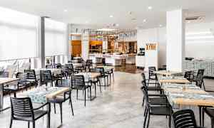 En matsal med bord och stolar samt dekorationer i taket. (AI-genererad text)