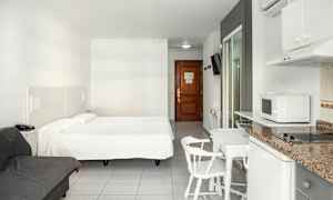 Ett hotellrum med en dubbelsäng, en soffa, matbord med stolar och ett pentry. (AI-genererad text)