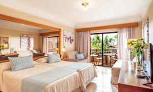 Hotellrum med två sängar, en sittgrupp och en balkong. (AI-genererad text)